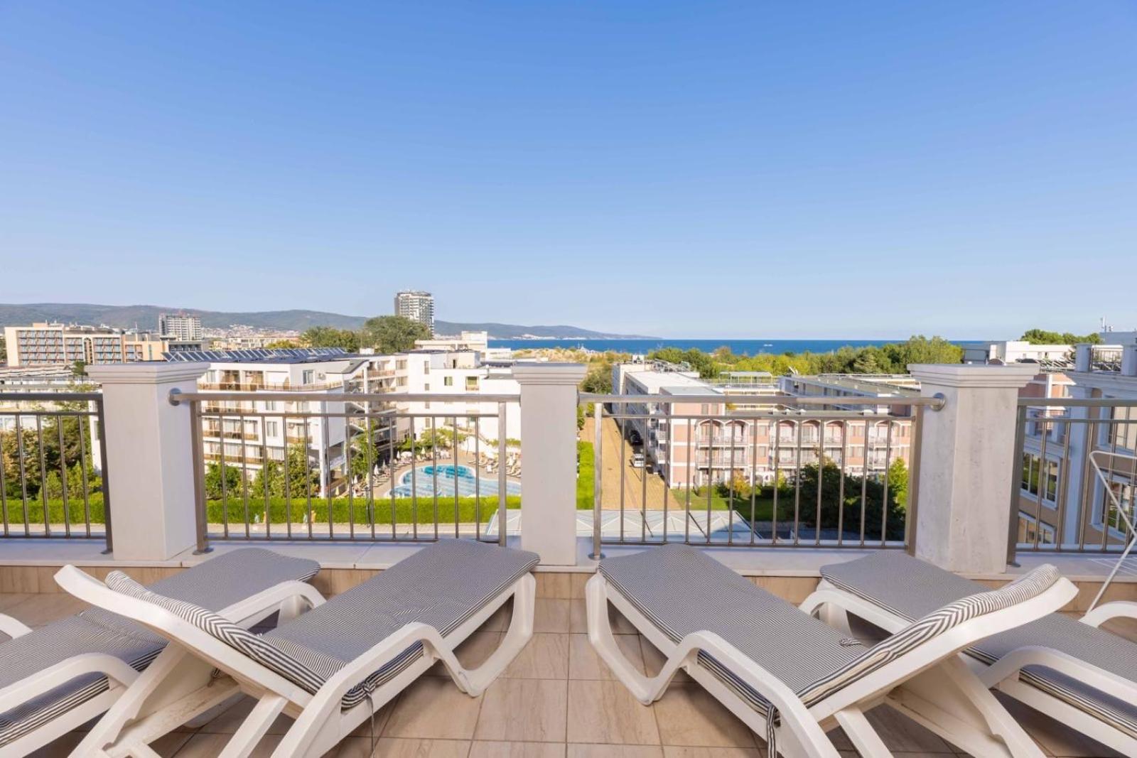 Plaša Rome Palace Deluxe viesnīcas jumta terase ar sauļošanās krēsliem un panorāmas skatu uz pilsētu un jūras horizontu