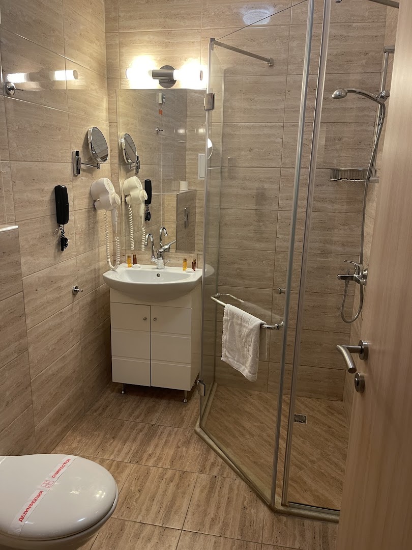 Rome Palace Deluxe numura vannas istaba ar dušas kabīni, izlietni, spoguli un fēnu, ieturēta siltos smilškrāsas toņos