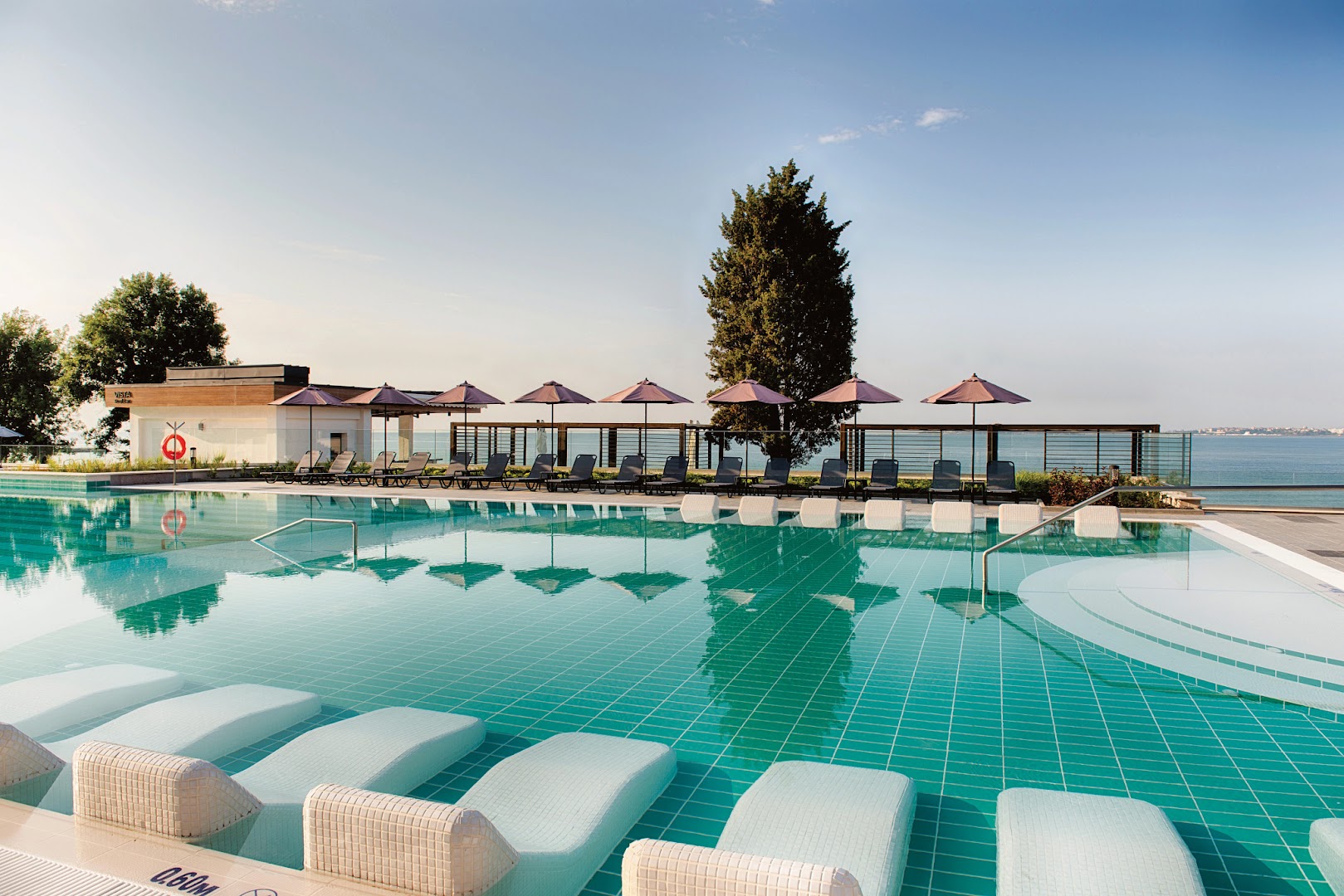 Alua Sunny Beach Resort & Spa bezgalības tipa baseins ar iebūvētiem zviļņiem un skatu uz jūras līci saulainā dienā