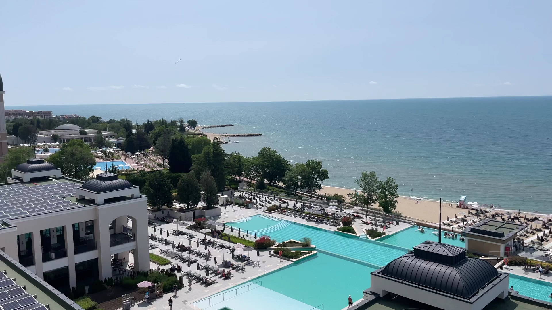 Skats no Alua Sunny Beach Resort & Spa augšējiem stāviem uz baseinu zonu, saulessargiem un smilšu pludmali pie Melnās jūras