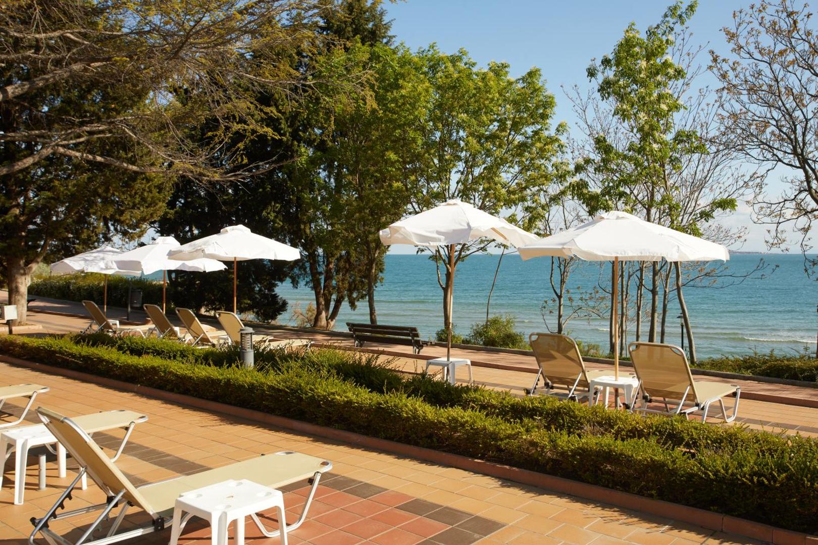 Alua Sunny Beach Resort & Spa atpūtas zona ar sauļošanās krēsliem un saulessargiem uz terases pie jūras krasta Bulgārijā