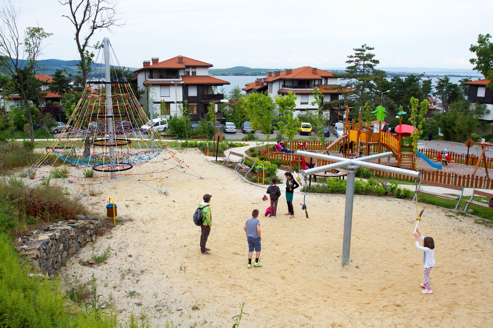 Viva Mare Beach Hotel bērnu rotaļu laukums ar kāpšanas tīkliem un slidkalniņiem — skats uz jūru un bungalo tipa ēkām