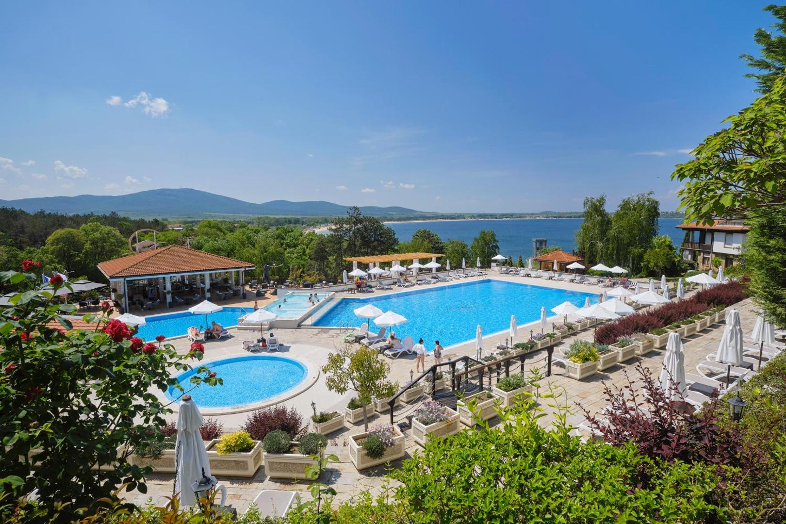 Viva Mare Beach Hotel āra baseinu komplekss ar skatu uz Melno jūru, saulessargiem un bāru piekrastes kūrortā