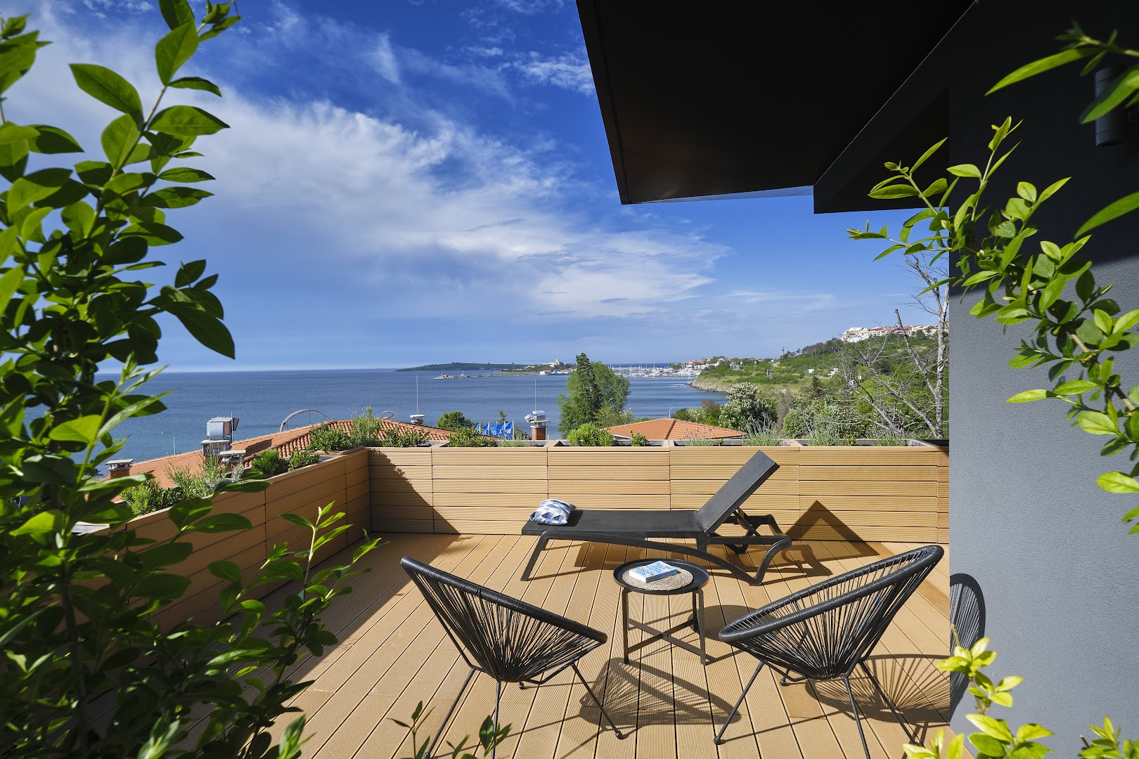 Viva Mare Beach Hotel numura terase ar skatu uz Melno jūru — koka klājs, sauļošanās krēsls un atpūtas mēbeles