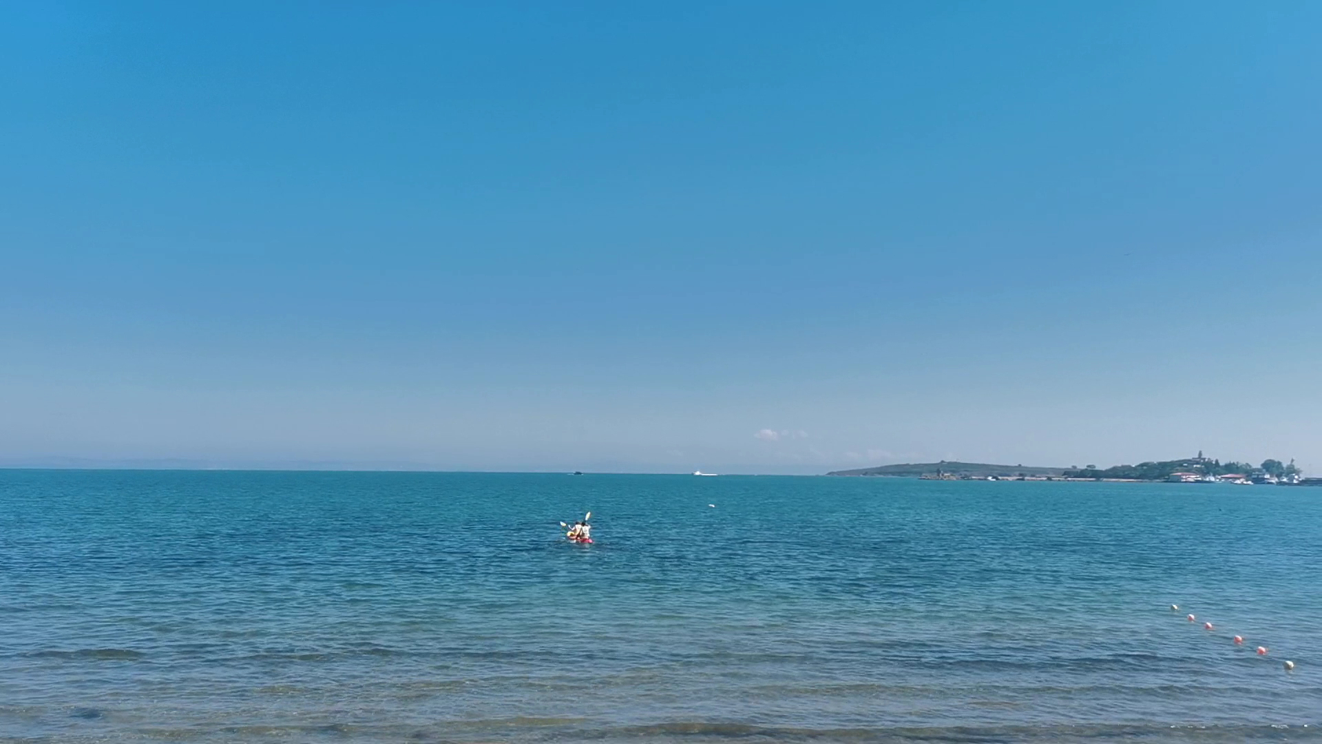 Skats uz Melno jūru no Viva Mare Beach Hotel piekrastes Sozopolē — dzidrs ūdens, tālumā redzama laiva un krasta līnija