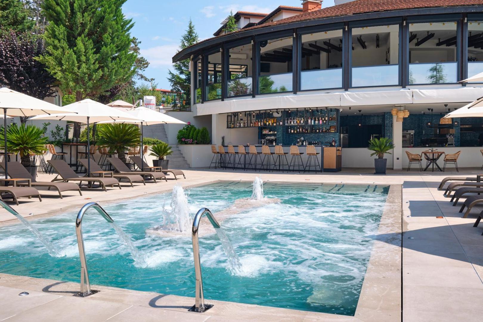 Viva Mare Beach Hotel baseins ar masāžas strūklām un bāru fonā, aprīkots ar sauļošanās krēsliem un saulessargiem