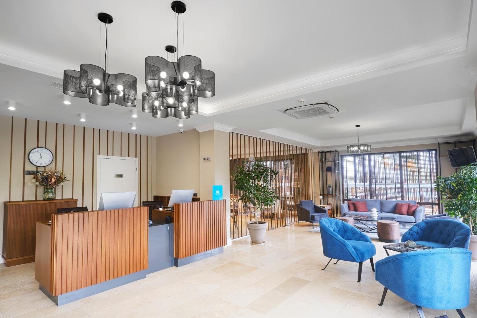 Viva Mare Beach Hotel modernā recepcijas zona un vestibils ar stilīgām mēbelēm, ziliem atpūtas krēsliem un dizaina gaismekļiem
