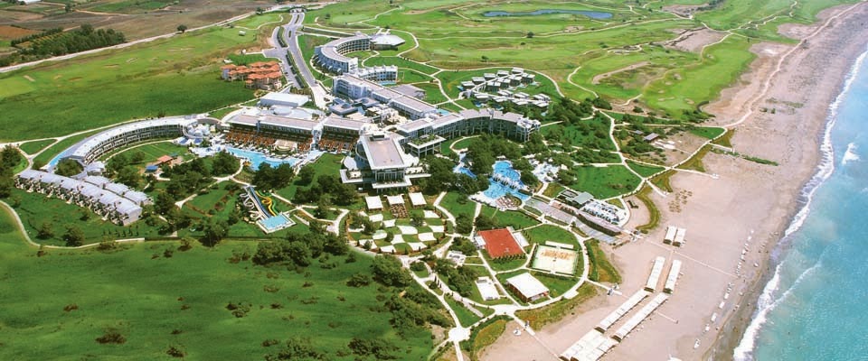 Lykia World Antalya kūrorta kopskats ar golfa laukumiem, galveno ēku kompleksu un garu smilšu pludmales joslu Vidusjūras krastā