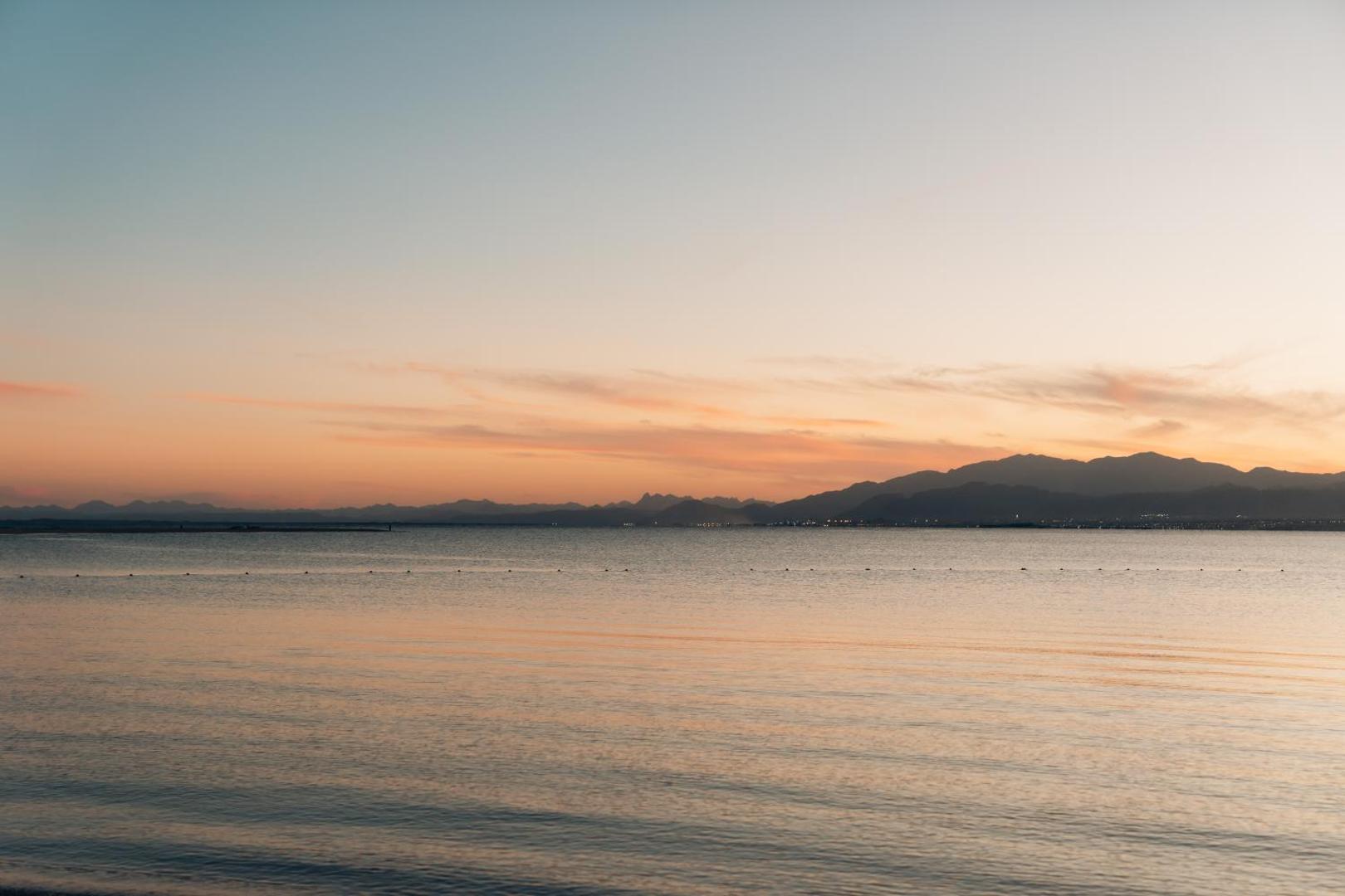 Saulriets virs Sarkanās jūras un kalnu siluetiem pie Sheraton Soma Bay Resort viesnīcas Somabejas kūrortā