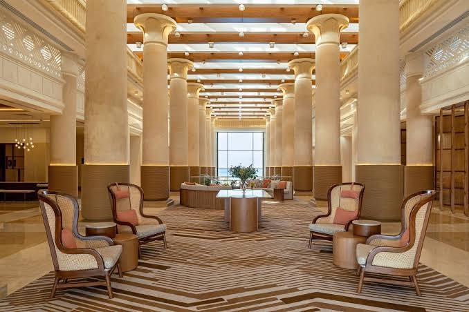 Sheraton Soma Bay Resort greznais vestibils ar augstām kolonnām un ērtiem atpūtas krēsliem — klasiska arhitektūra un plašuma sajūta
