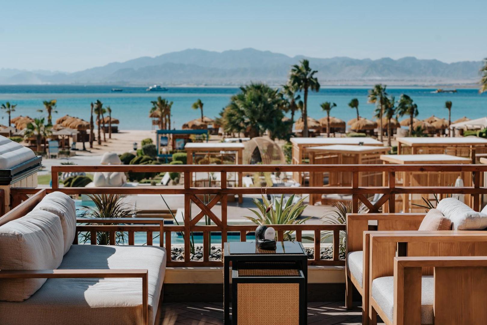 Skats no Sheraton Soma Bay Resort terases uz pludmali, palmām un kalniem tālumā Somabejas līcī
