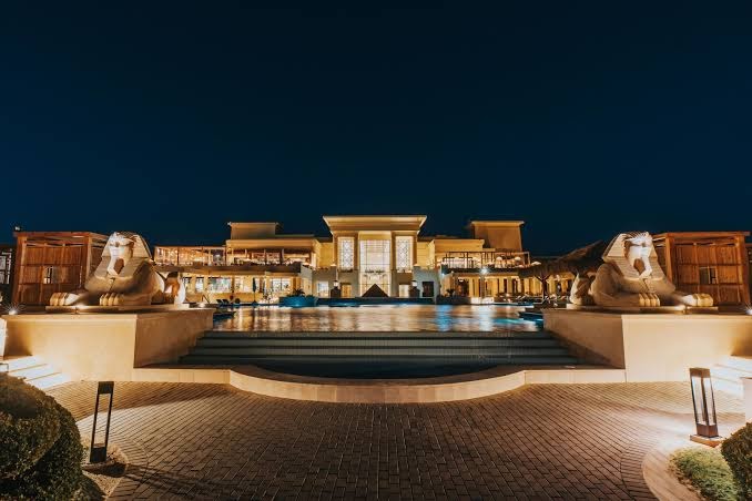 Sheraton Soma Bay Resort galvenā ēka un baseins vakarā ar izgaismotām sfinksu statujām un arhitektūru Somabejā, Ēģiptē