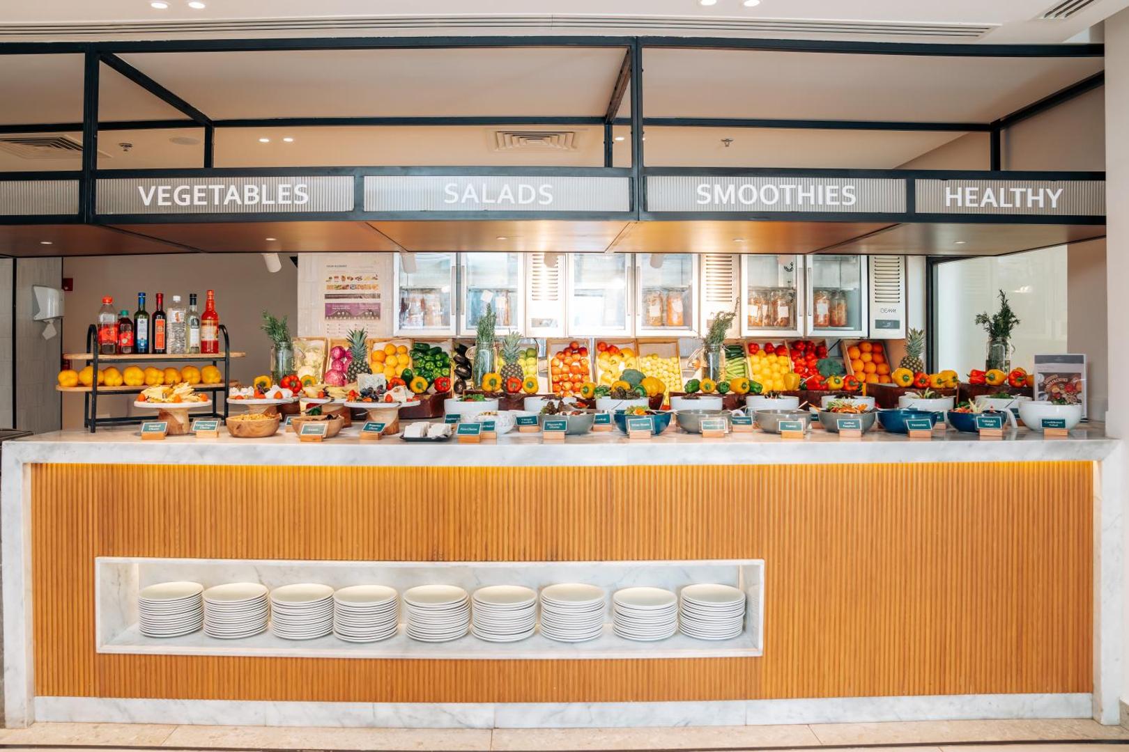 Mūsdienīgs restorāna interjers Sheraton Soma Bay Resort viesnīcā ar veselīgā uztura stendu — salāti, smūtiji un svaigi produkti viesu izvēlei