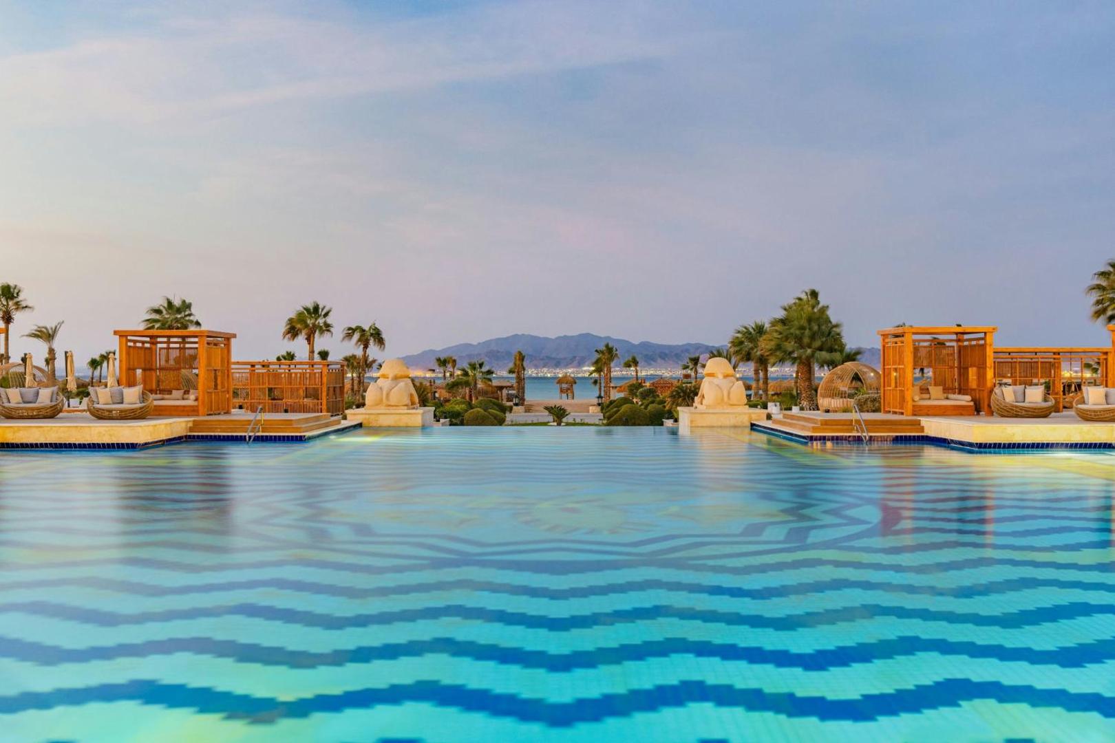 Sheraton Soma Bay Resort baseins ar pārplūdes malu un skatu uz Sarkano jūru un kalniem saulrietā, Somabejas kūrorts
