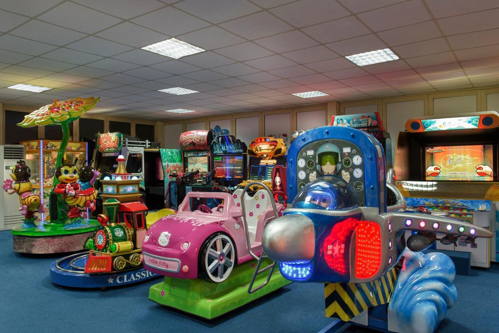 Megasaray Club Belek bērnu izklaides centrs ar krāsainiem spēļu automātiem, karuseļiem un lidmašīnas simulatoru iekštelpās