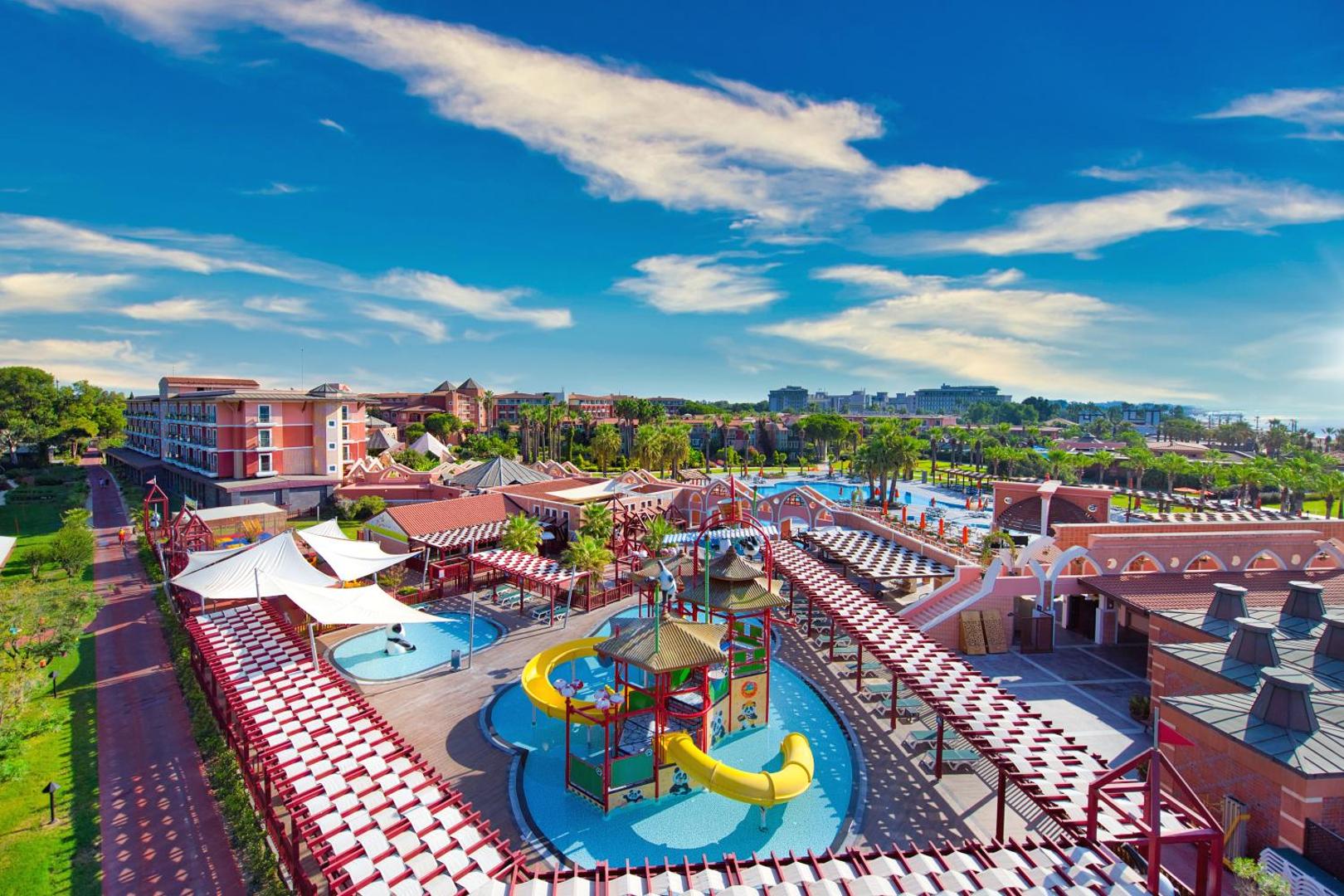Megasaray Club Belek teritorijas skats no augšas ar bērnu baseinu un rotaļu laukumu — droša vide ģimenes atpūtai