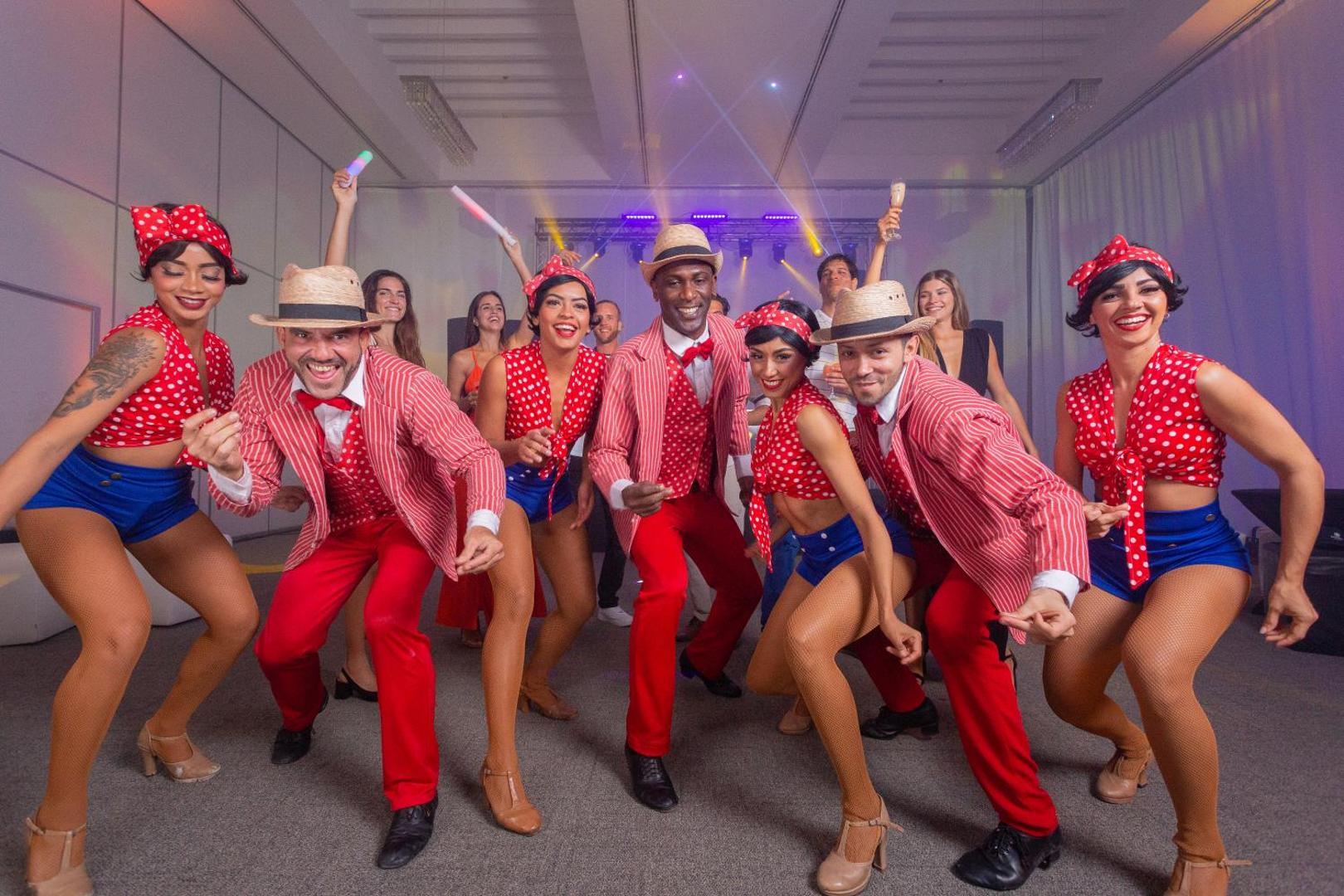Sandos Cancun viesnīcas izklaides šovs ar dejotājiem sarkanbalti svītrainos tērpos un punktotās vestēs iekštelpu pasākumu zālē Kankunā, Meksikā.