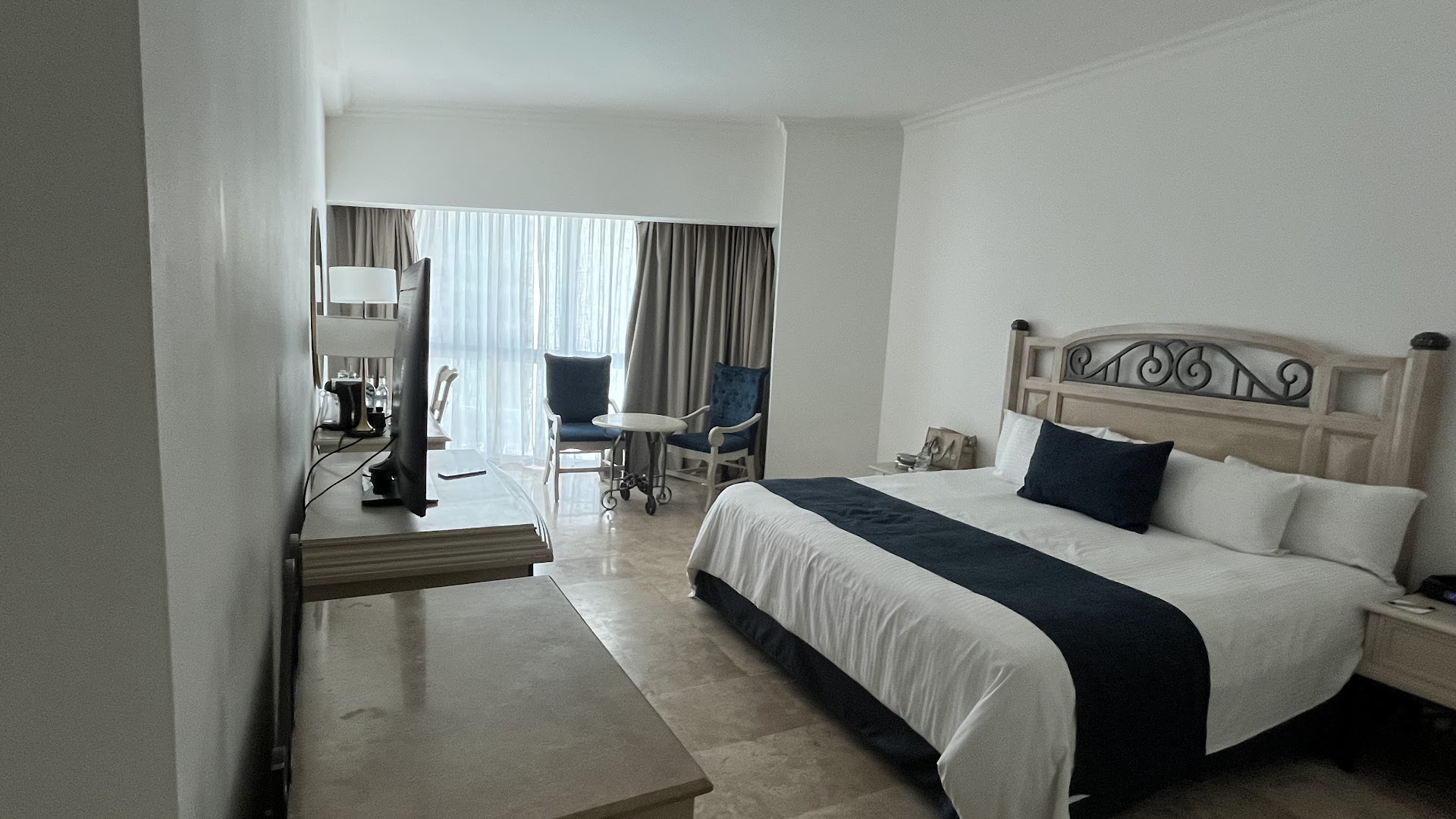 Sandos Cancun elegants numurs ar lielu gultu, tumši ziliem akcentiem un skatu uz balkonu Kankūnas piekrastē