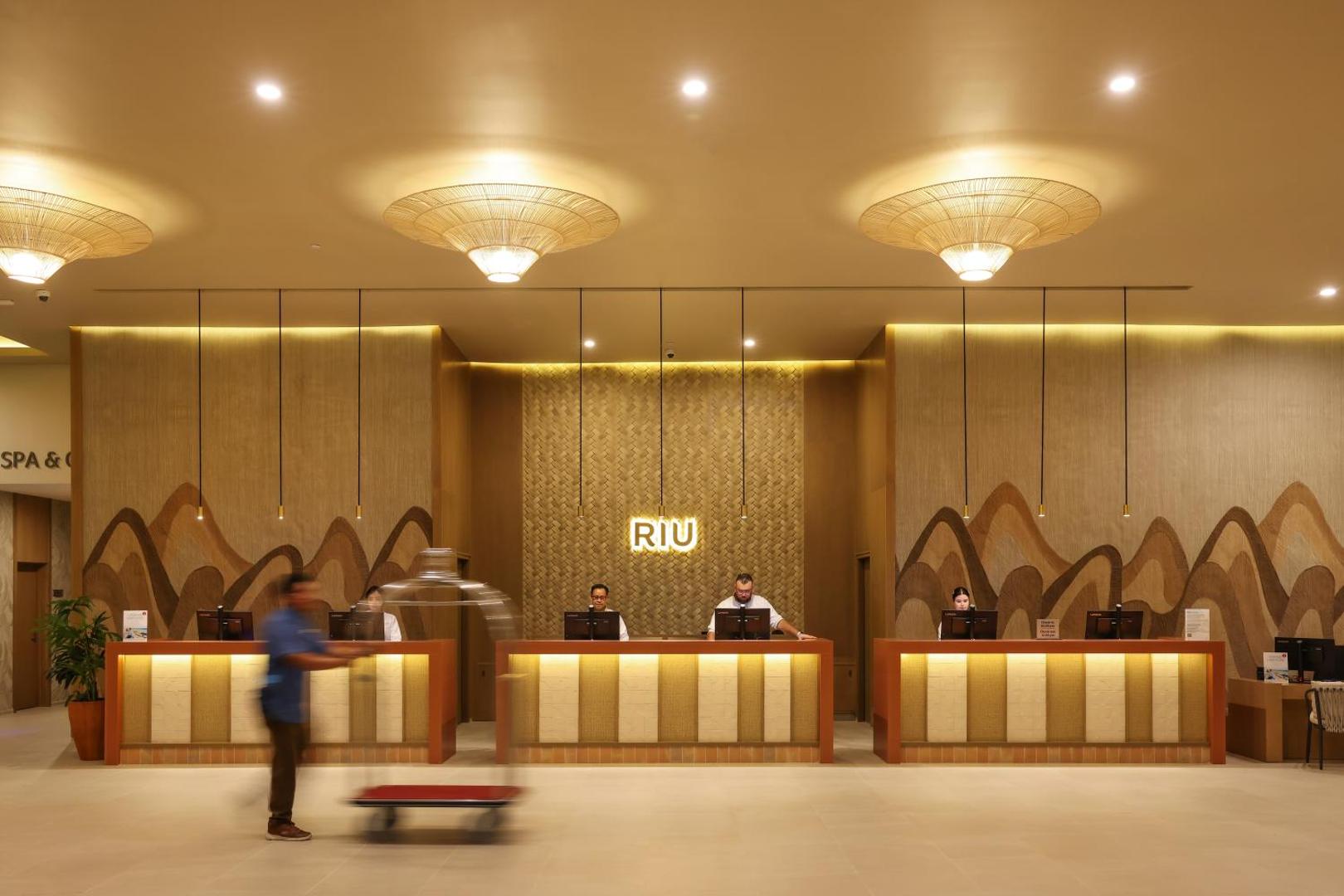 RIU Ventura viesnīcas recepcijas zona ar laipnu personālu un siltu, mājīgu apgaismojumu viesu sagaidīšanai.