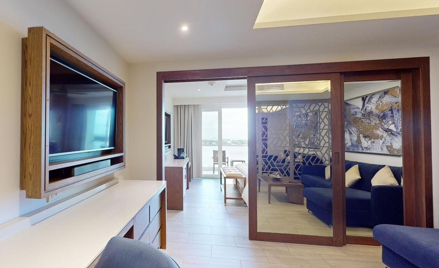 Royalton CHIC Cancun numurs ar atsevišķu atpūtas zonu, stikla bīdāmajām durvīm un skatu uz okeānu Kankunas piekrastē