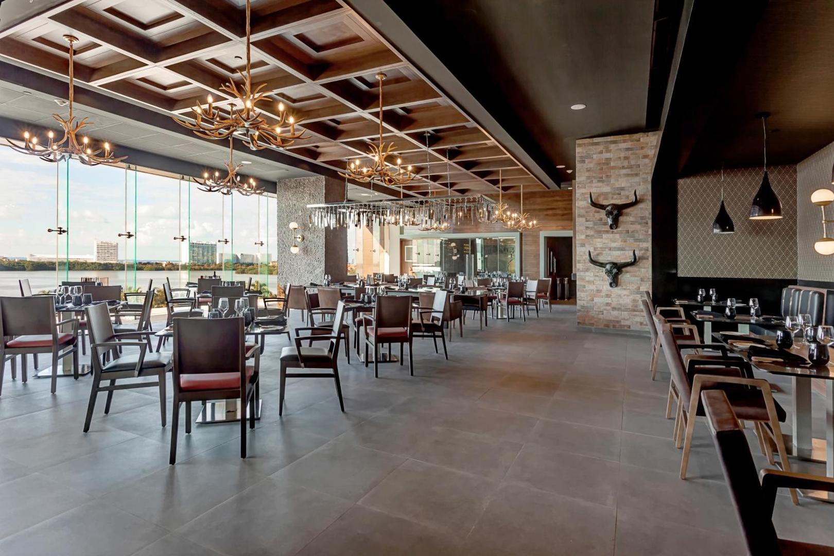 Royalton CHIC Cancun tematisks restorāns ar koka griestiem, raga stila lustrām un skatu uz pilsētas lagūnu