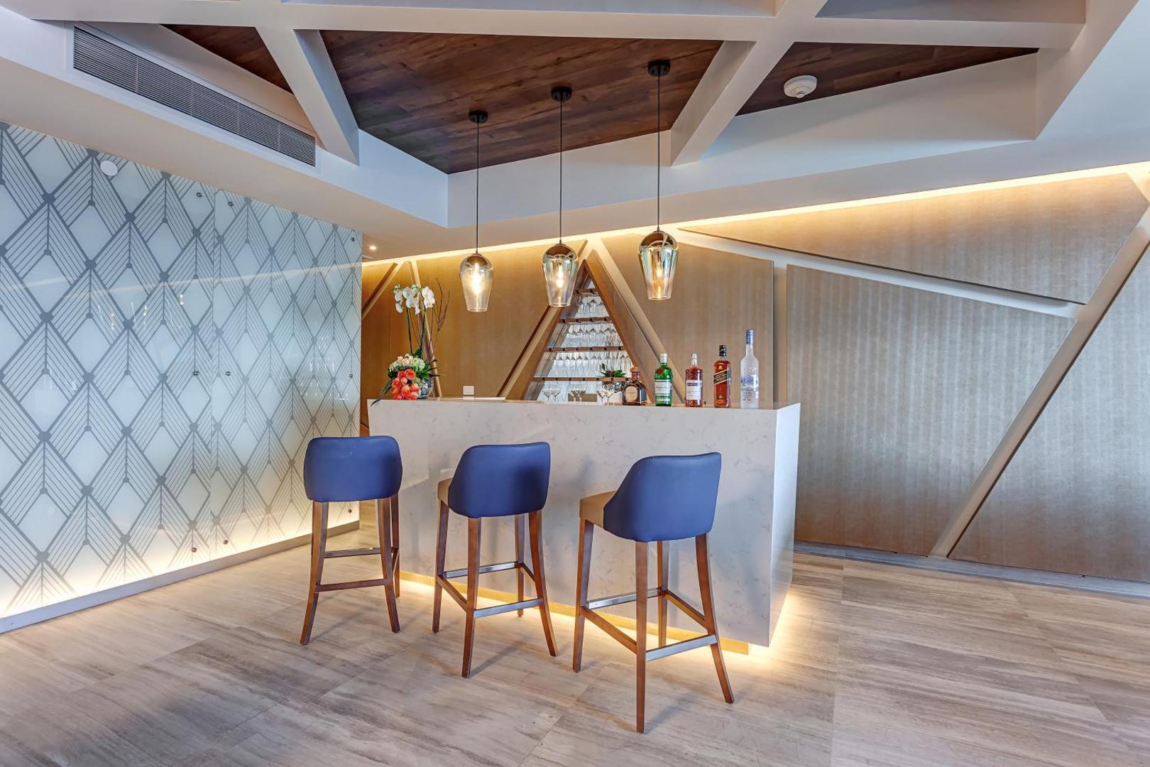Royalton CHIC Cancun modernais lobby bārs ar marmora leti, ziliem bāra krēsliem un dizaina apgaismojumu Kankunā, Meksikā.