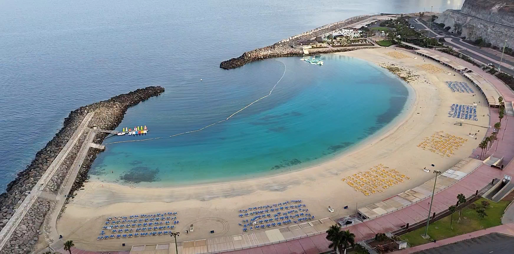RIU Vistamar skats no augšas uz Playa de Amadores līci Grankanārijā — tirkīzzils ūdens, smilšu pludmale un saulessargi