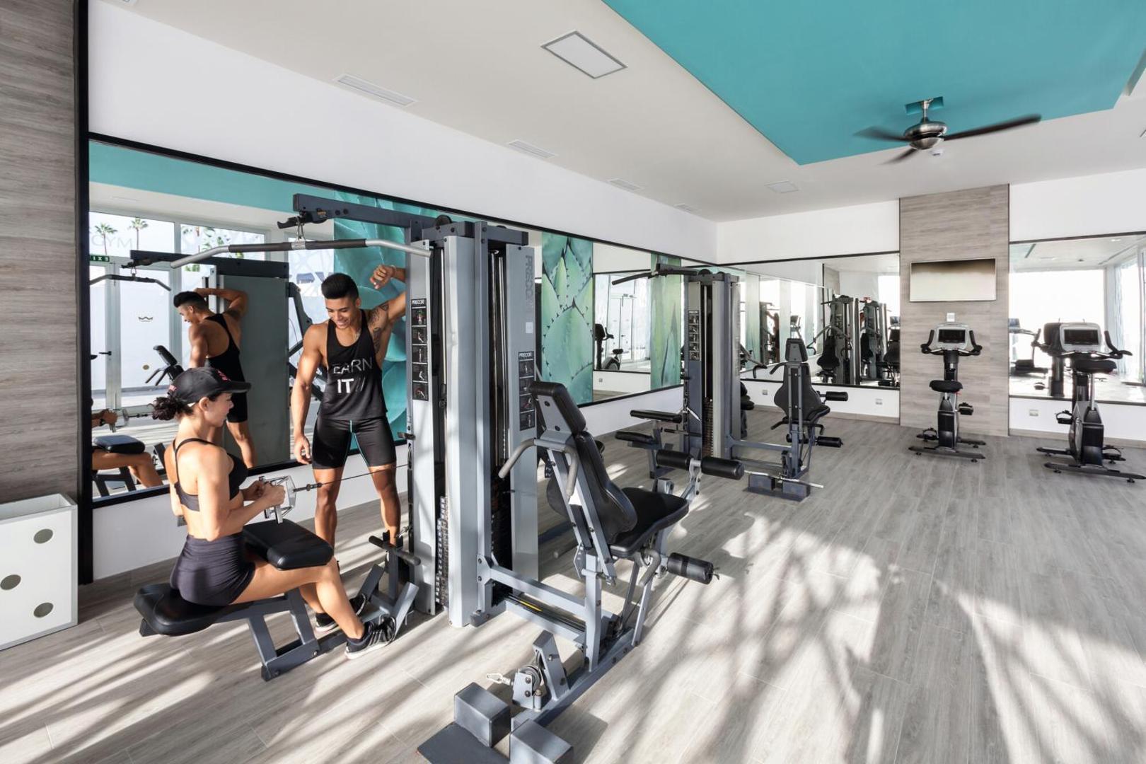 RIU Vistamar fitnesa zāle ar moderniem trenažieriem un lieliem spoguļiem — gaiša telpa aktīvai atpūtai un treniņiem