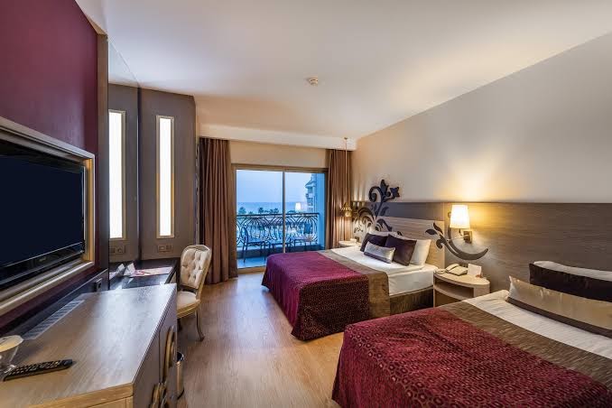 Kirman Hotels Belazur Resort & Spa numurs ar divām gultām, balkonu un skatu uz jūru Belekā, Turcijā — gaišs interjers ar TV