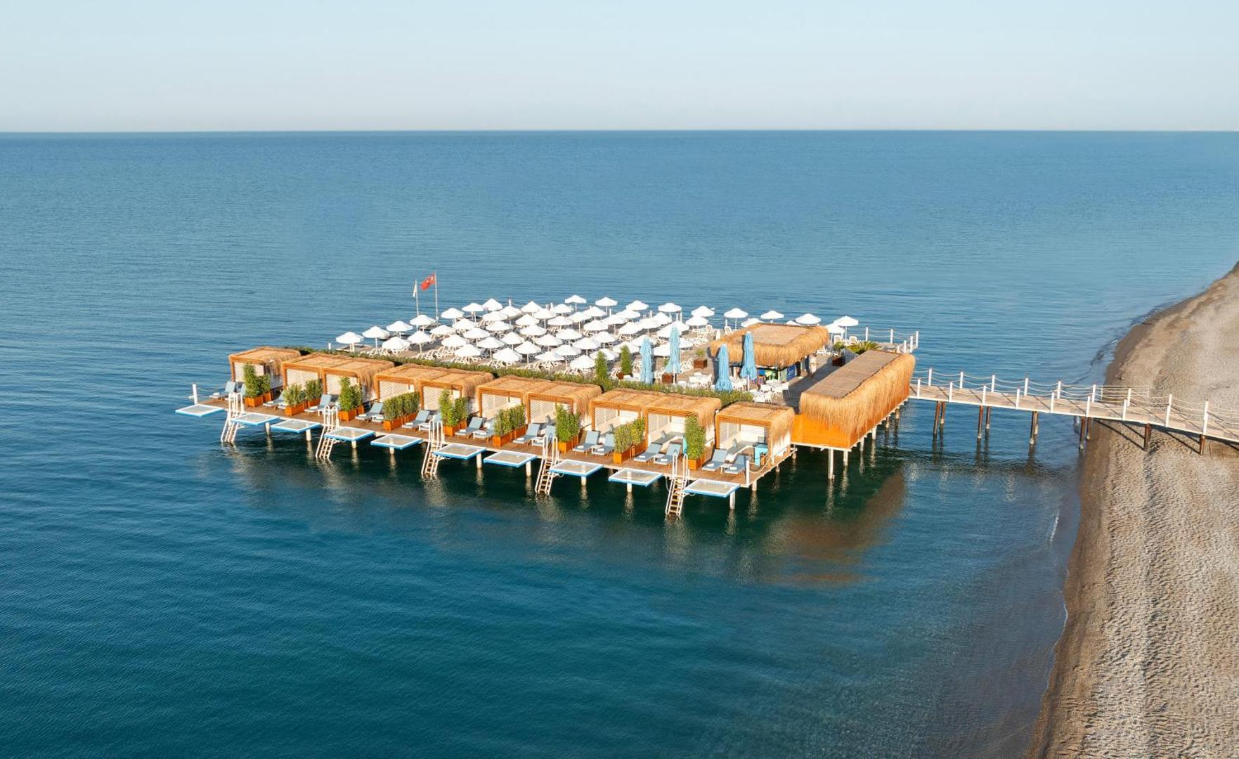 Kirman Hotels Belazur Resort & Spa privātā koka piestātne jūrā ar atpūtas bungalo un saulessargiem Belekas piekrastē