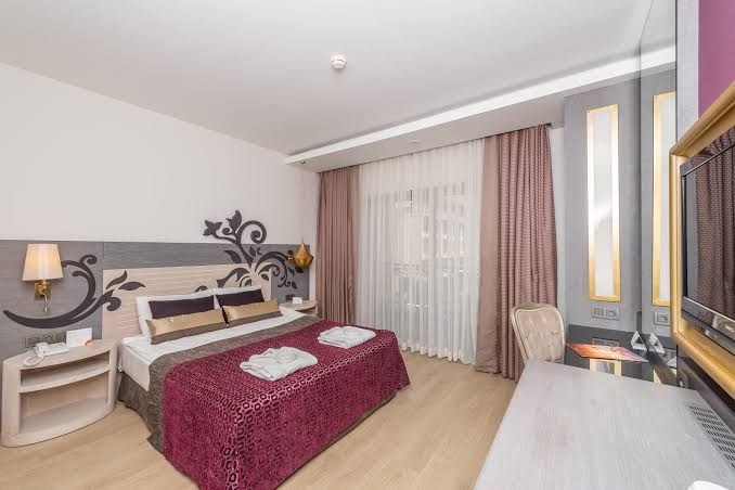 Kirman Hotels Belazur Resort & Spa mājīgs divvietīgs numurs ar modernu apgaismojumu un darba zonu — skats uz logu ar aizkariem