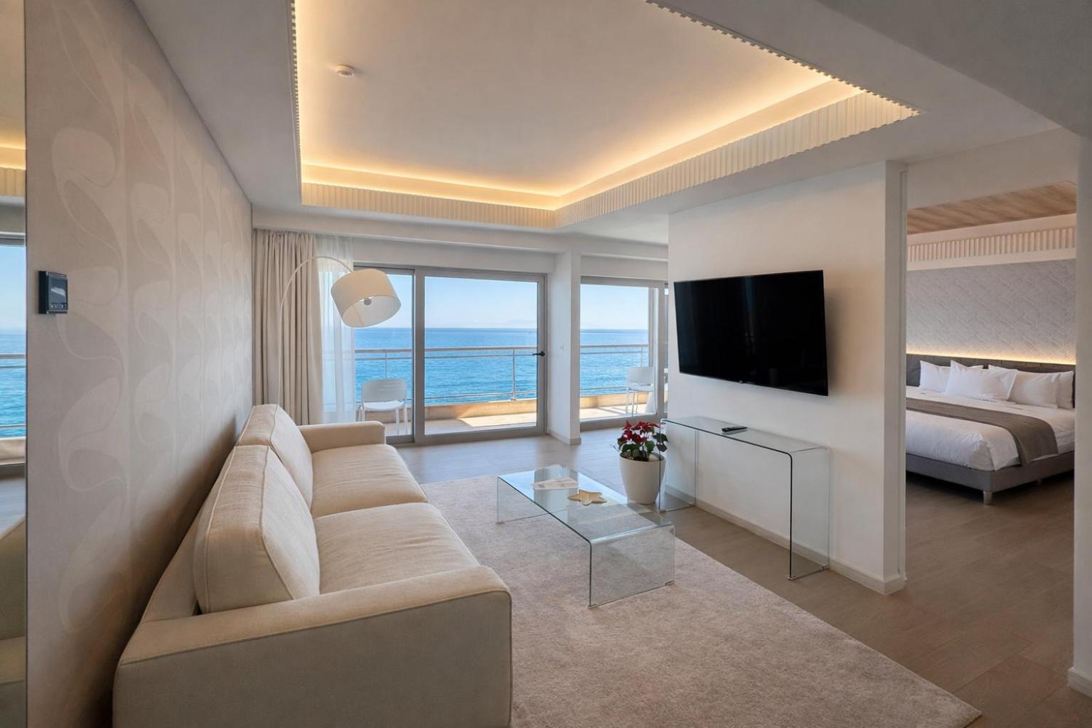 Plašs Mediterranean Hotel luksusa numurs ar atsevišķu viesistabas zonu, dīvānu un panorāmas skatu uz jūru caur lielajiem logiem