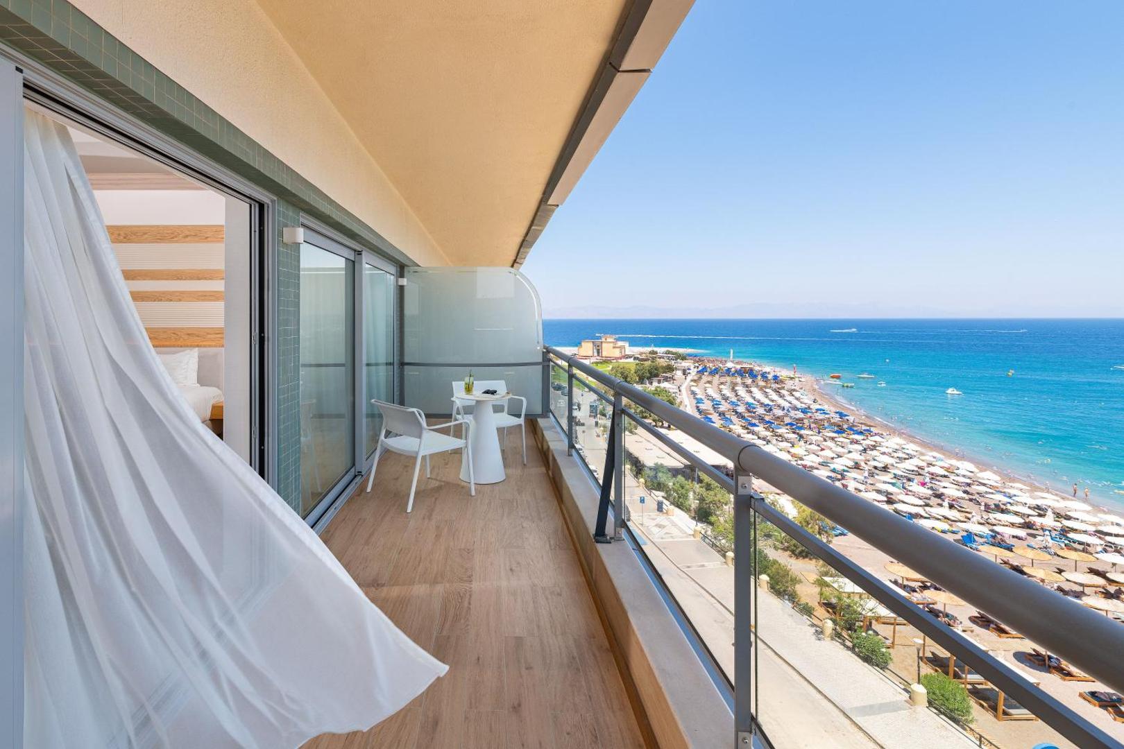 Mediterranean Hotel numura balkons ar skatu uz jūru un Rodas smilšu pludmali — mēbelēta atpūtas zona ar krēsliem un galdiņu