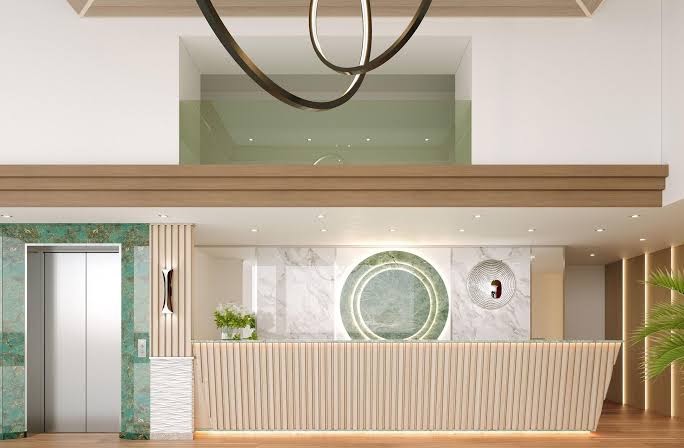 Mediterranean Hotel modernā recepcijas zona ar gaišu koka apdari, marmora sienu un stilīgu apgaismojumu Rodas pilsētā, Grieķijā.