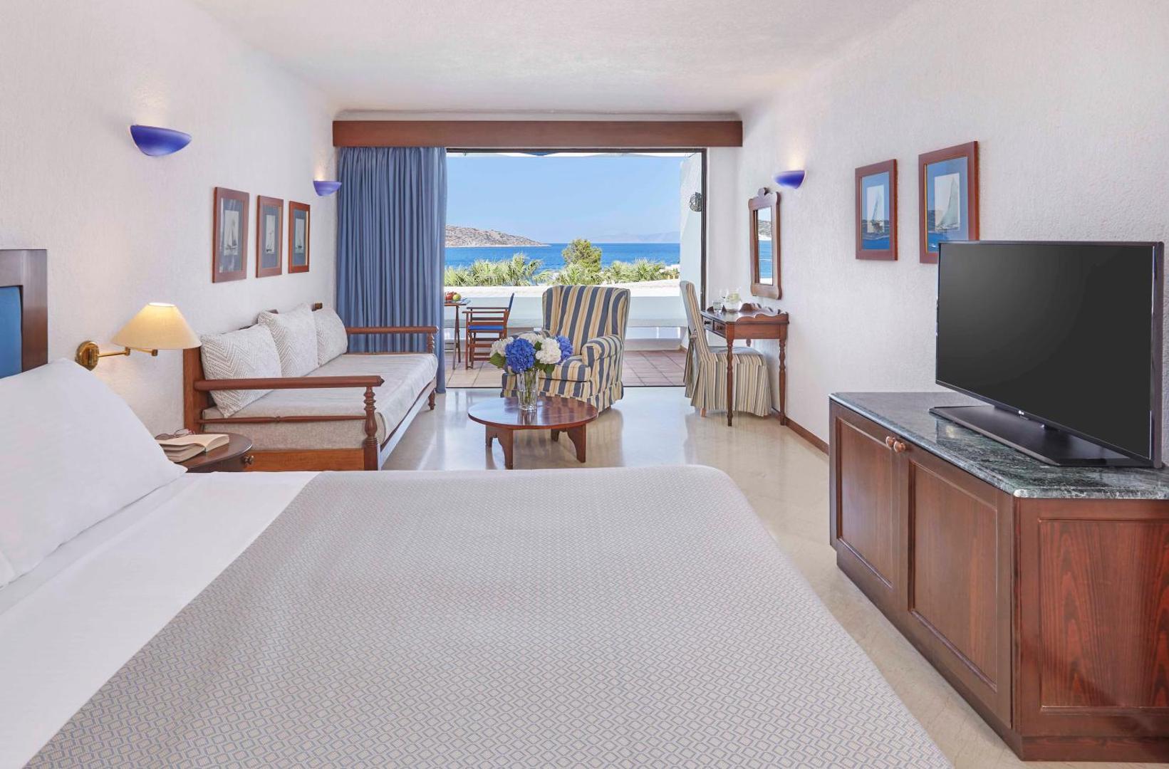 Elounda Bay Palace Hotel klasiska stila numurs ar skatu uz zilo jūru — plaša terase un eleganta atpūtas zona