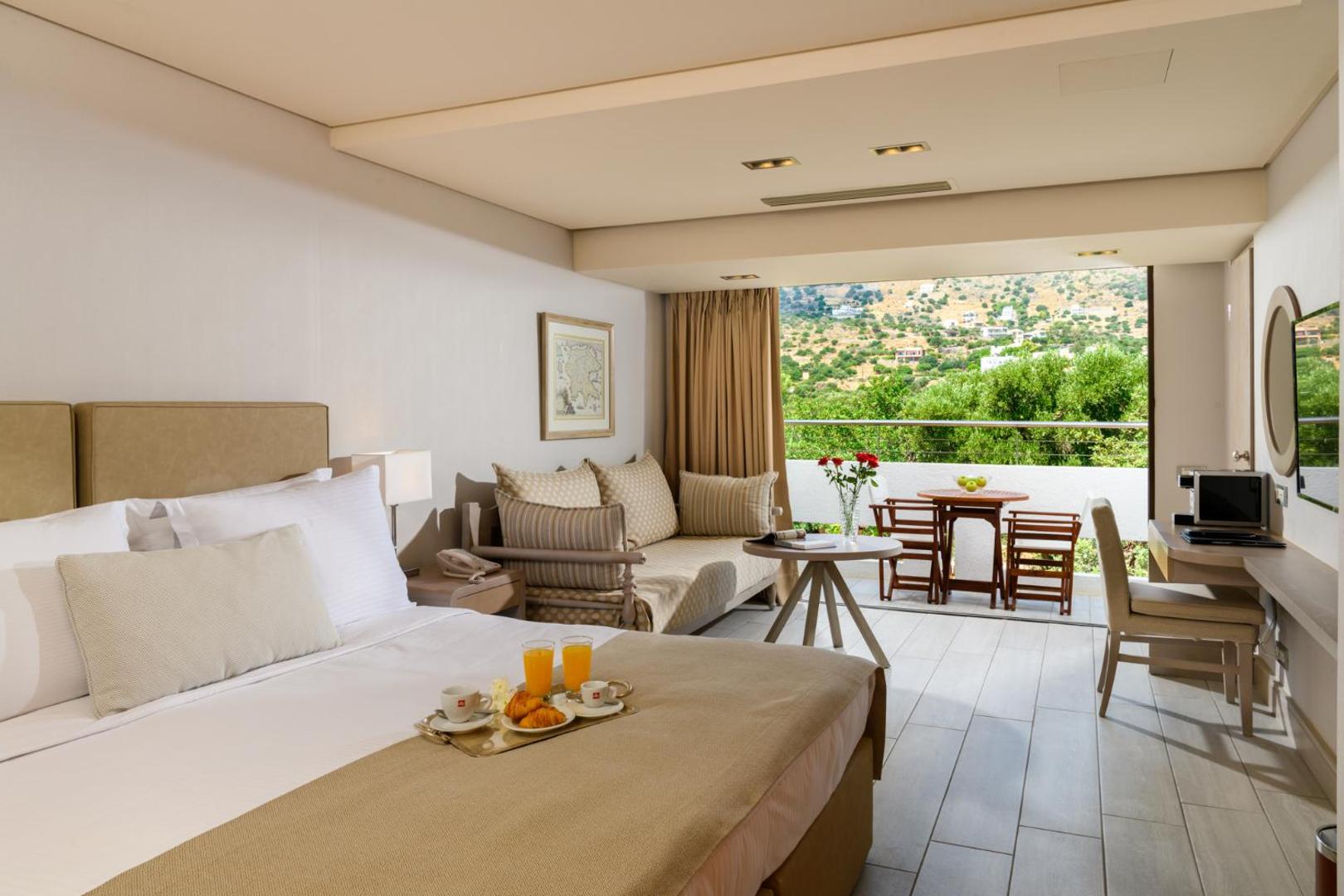 Elounda Bay Palace Hotel gaišs numurs ar balkonu un skatu uz Krētas kalniem — brokastis uz paplātes un mājīga atpūtas zona