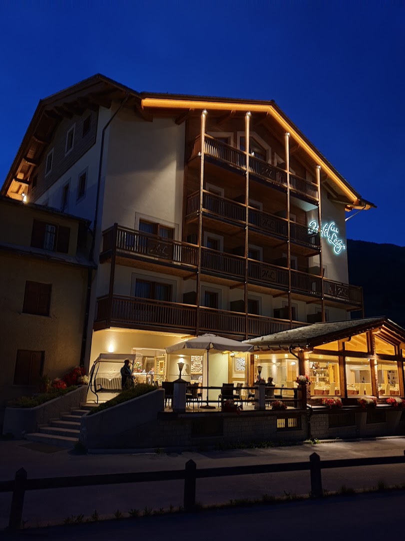 Hotel Lanz fasāde vakarā ar izgaismotiem balkoniem un āra terasi Livinjo kūrortā — mājīga atmosfēra un koka arhitektūra