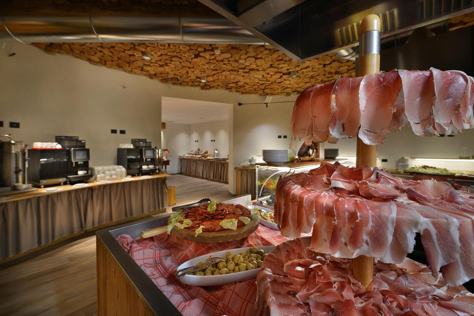 Alpen Resort Bivio brokastu bufete ar plašu vietējo gaļas izstrādājumu izvēli, sieriem un kafijas automātiem restorāna telpās