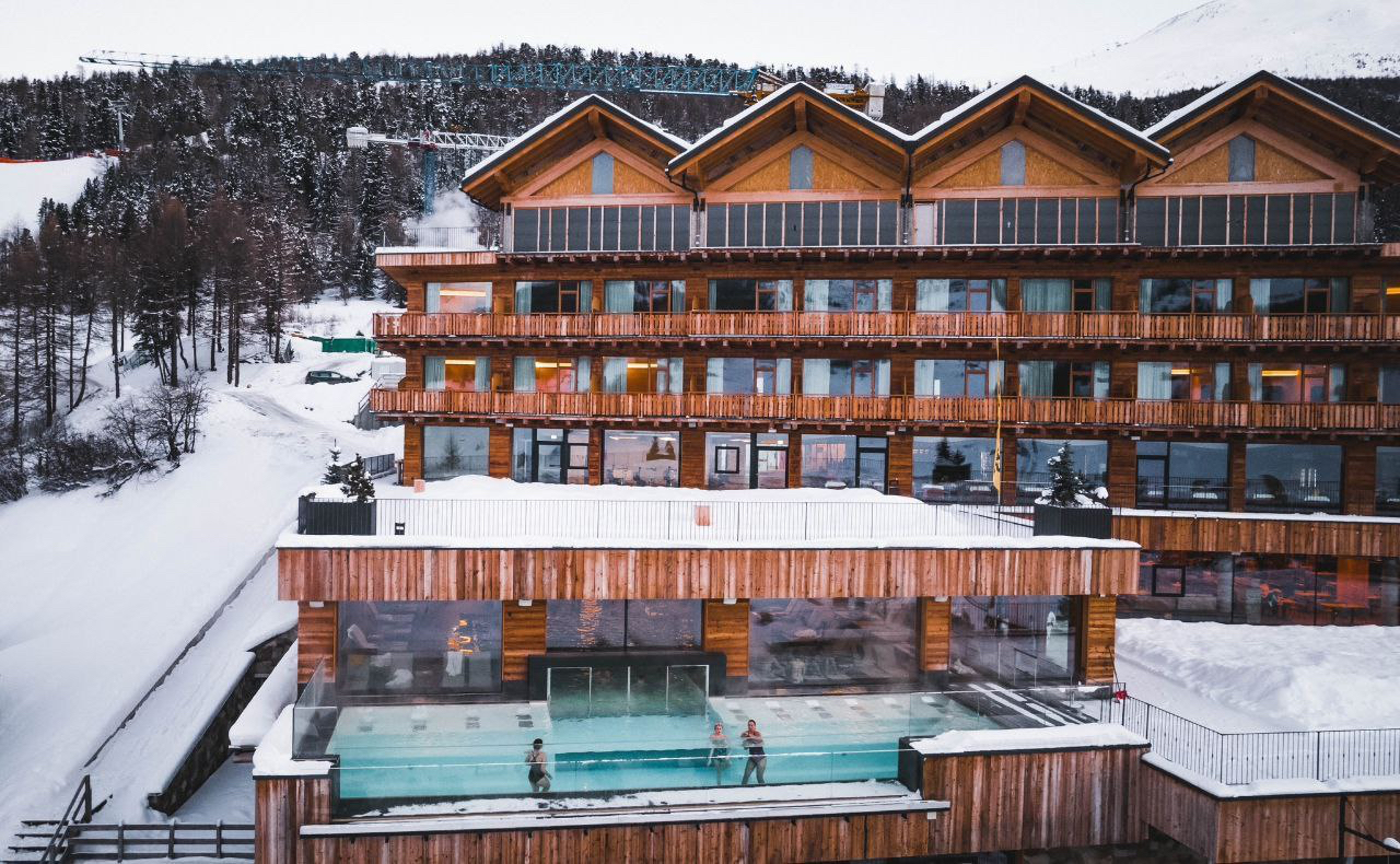 Alpen Resort Bivio fasāde un spa zona ar apsildāmu baseinu vakarā — sniegota vide un mājīgs koka dizains Livinjo kūrortā