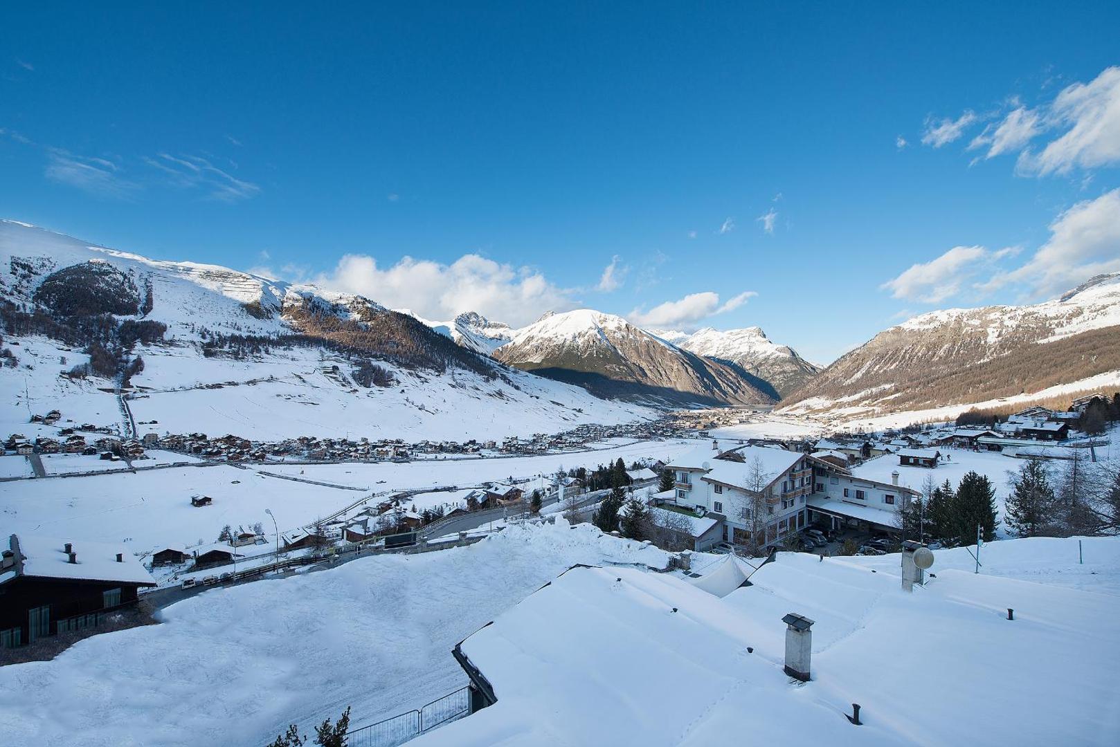 Panorāmas skats no Alpen Resort Bivio terases uz sniegoto Livinjo ciematu un apkārtējiem Itālijas Alpu kalniem