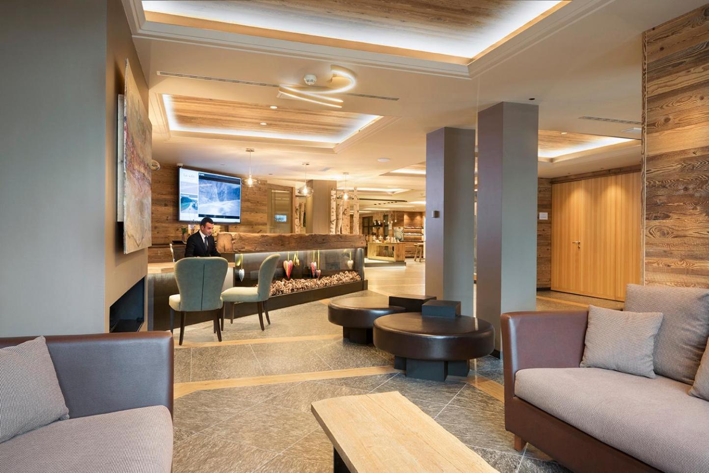 Lac Salin Spa & Mountain Resort modernā lobby zona ar koka apdari, ērtiem dīvāniem un viesnīcas reģistratūras galdu Livinjo