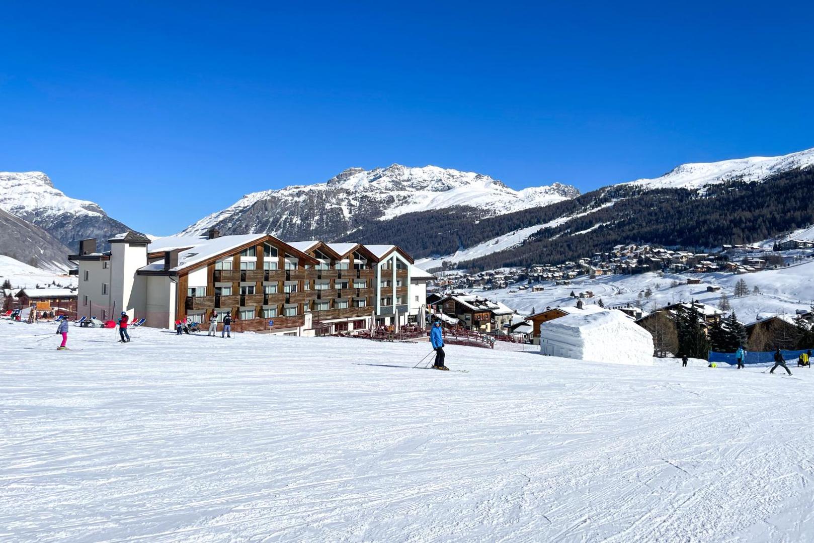 Lac Salin Spa & Mountain Resort ēka tieši pie slēpošanas trases Livinjo — kalnu ainava, sniegotas virsotnes un slēpotāji saulainā dienā