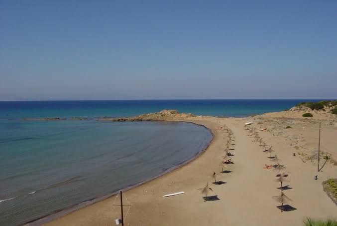 Brati Arkoudi Hotel privātā smilšu pludmale Peloponēsas piekrastē ar saulessargiem un dzidru jūras ūdeni līcī