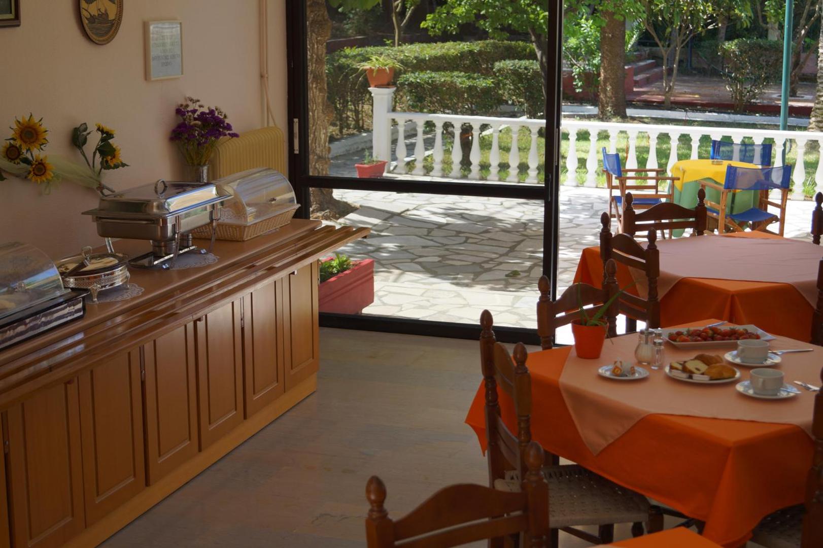 Brati Arkoudi Hotel restorāna iekštelpas ar skatu uz zaļojošu āra terasi un dārzu