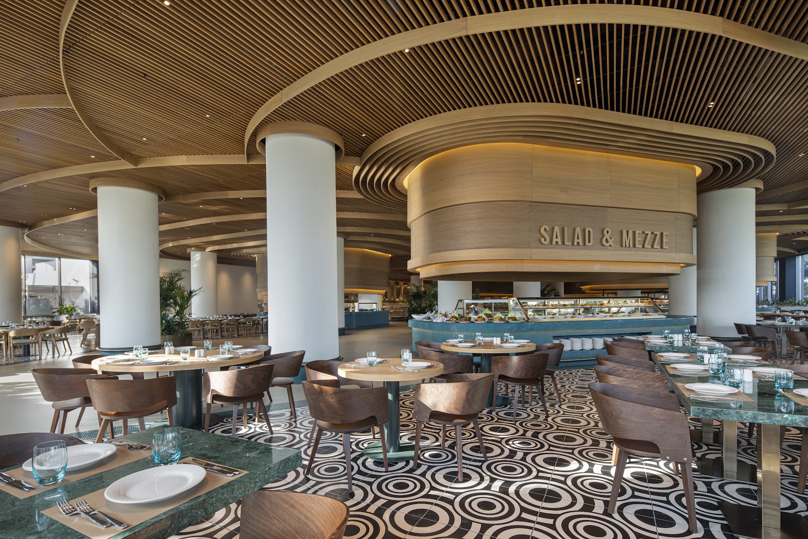 Voyage Belek Golf & Spa bufetes tipa restorāns ar salātu un uzkodu zonu, rakstainu grīdu un koka krēsliem