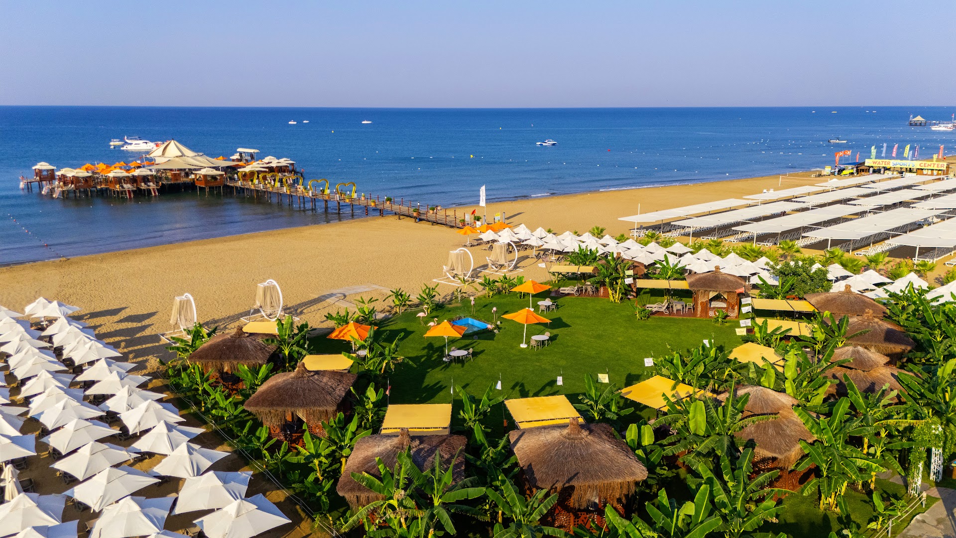 Von Resort Golden Coast pludmales zona ar saulessargiem, zālāju, palmām un koka piestātni jūrā