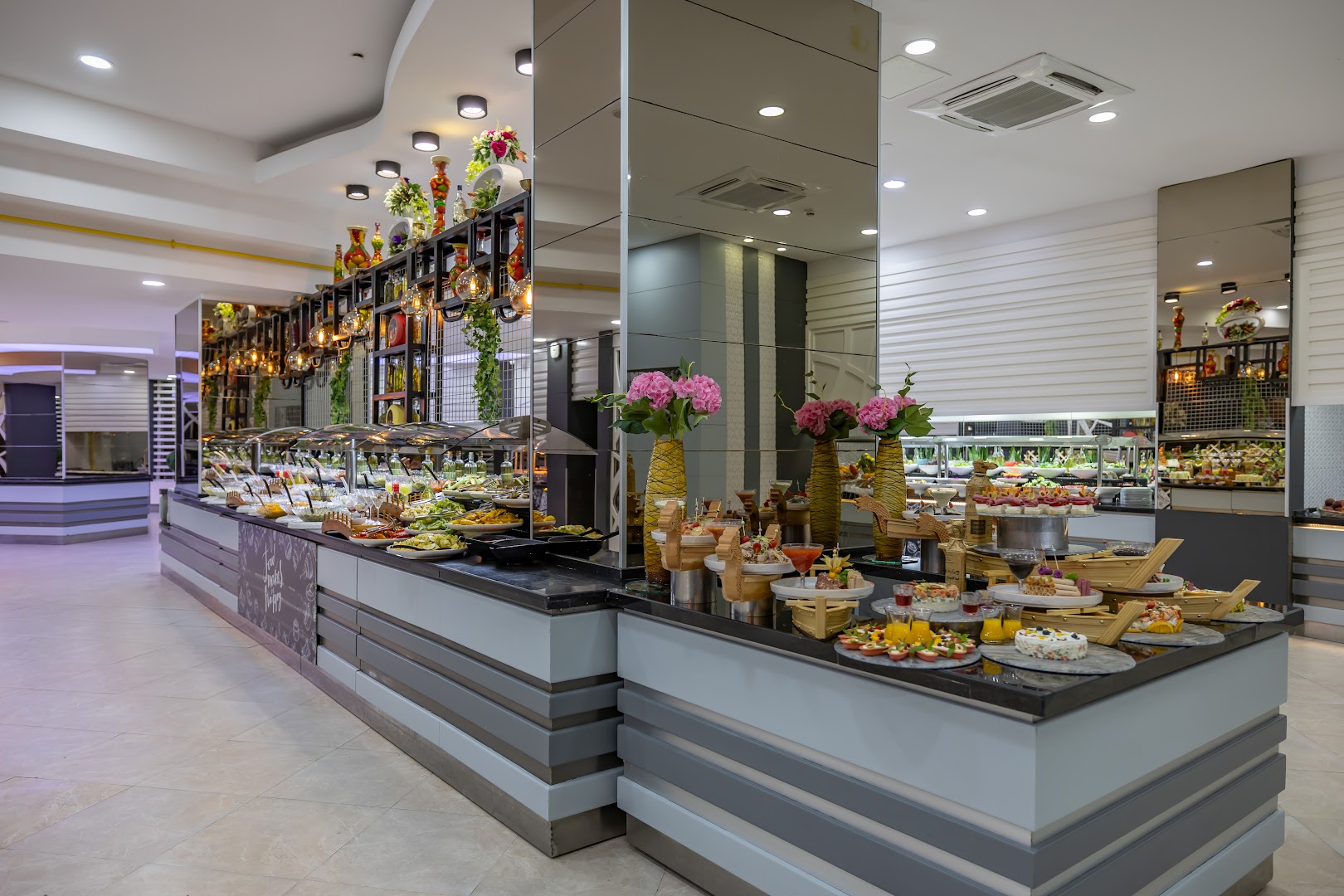 Von Resort Golden Coast galvenā restorāna bufetes zona ar plašu uzkodu, salātu un desertu izvēli modernā interjerā