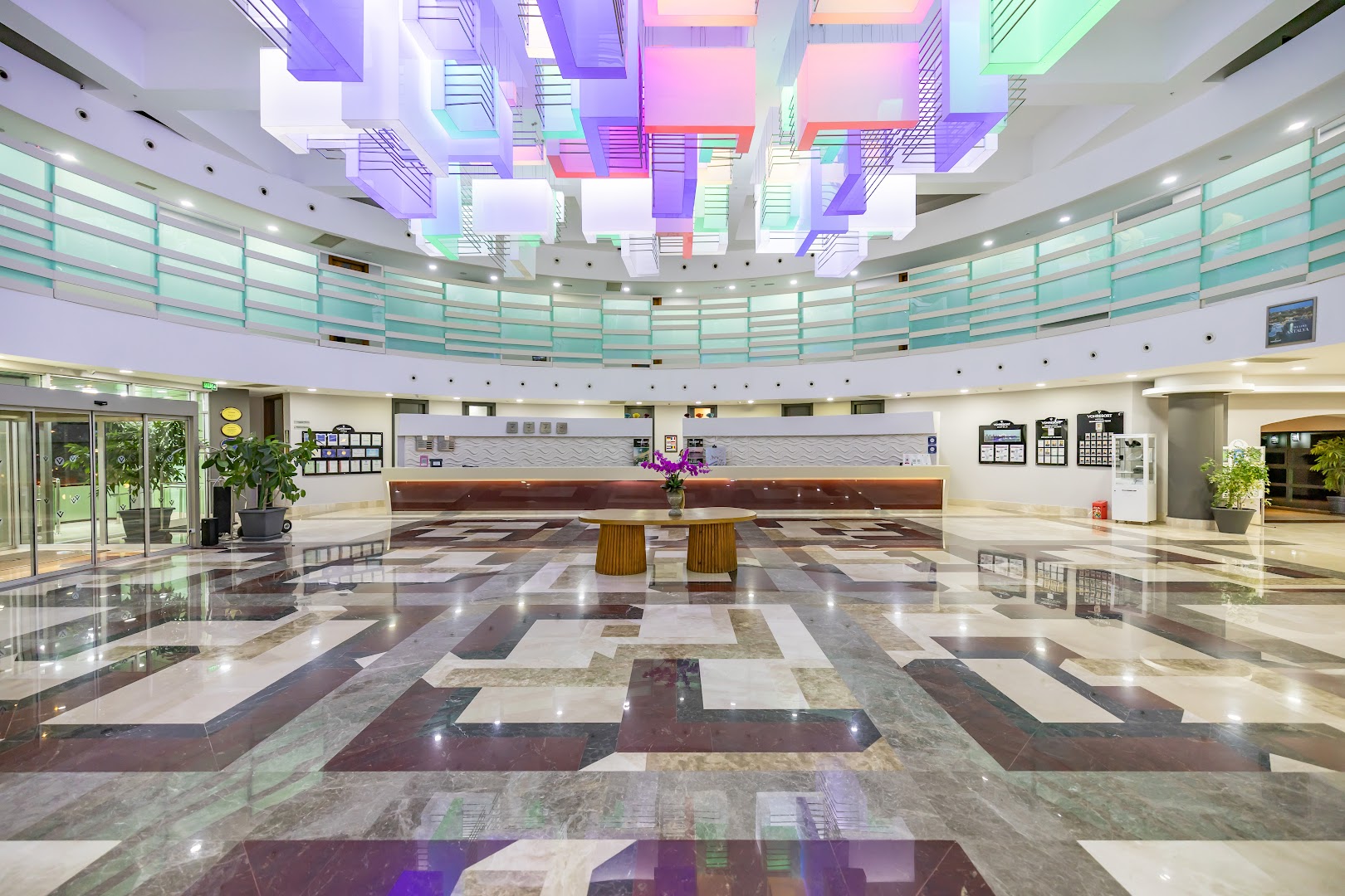 VONRESORT Golden Coast plašā recepcijas zona ar modernu krāsainu griestu instalāciju un marmora grīdu Antaljas reģionā, Turcijā