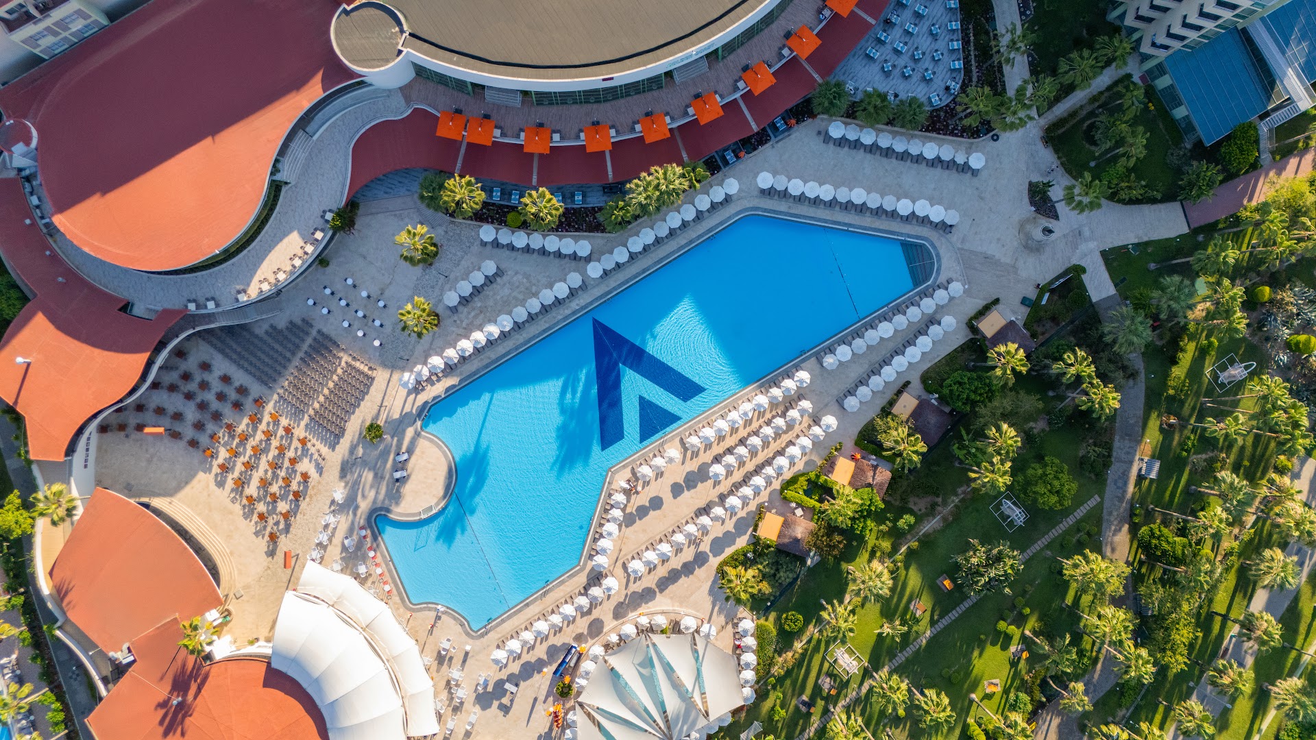 Viesnīcas VONRESORT Golden Coast baseina zonas skats no augšas, parādot sauļošanās terases, restorāna zonu un palmu alejas