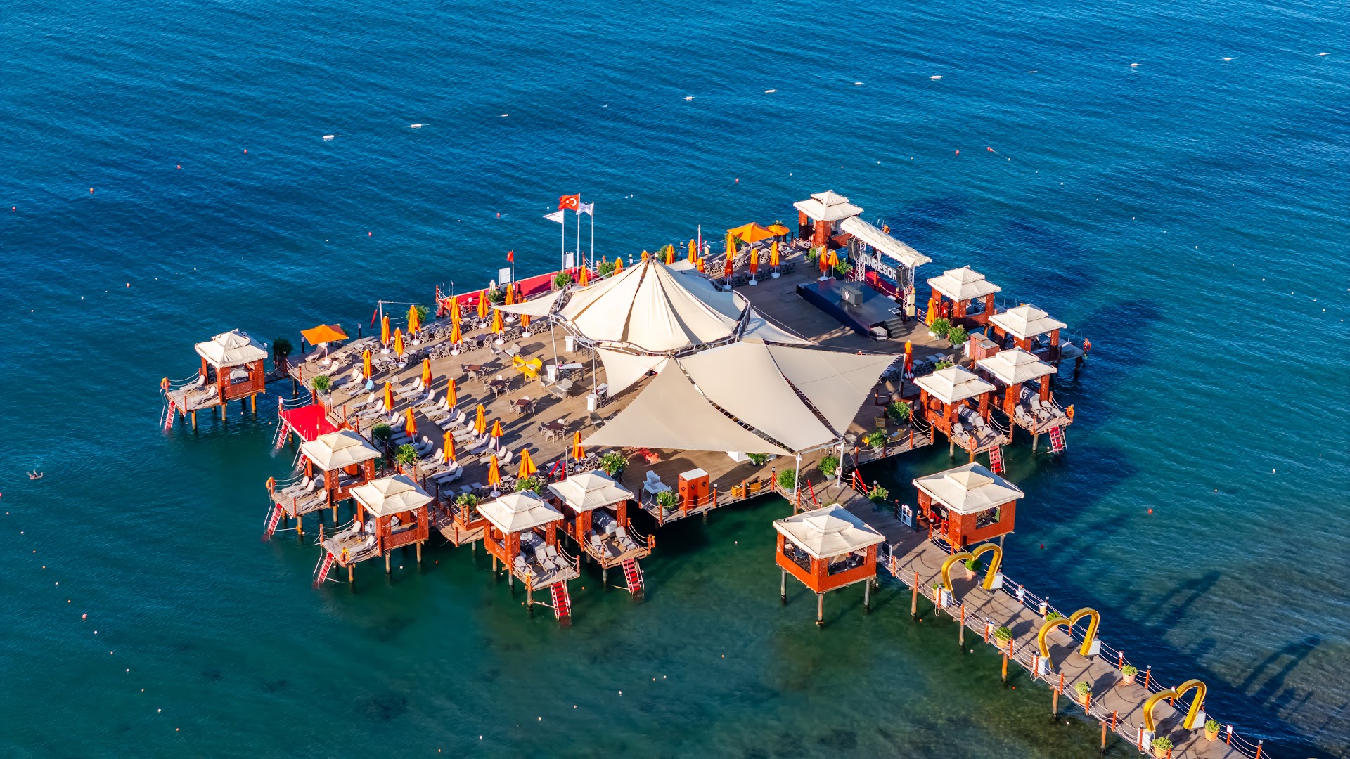 Von Resort Golden Coast koka piestātne jūrā ar atpūtas nojumēm, sauļošanās krēsliem un bāru
